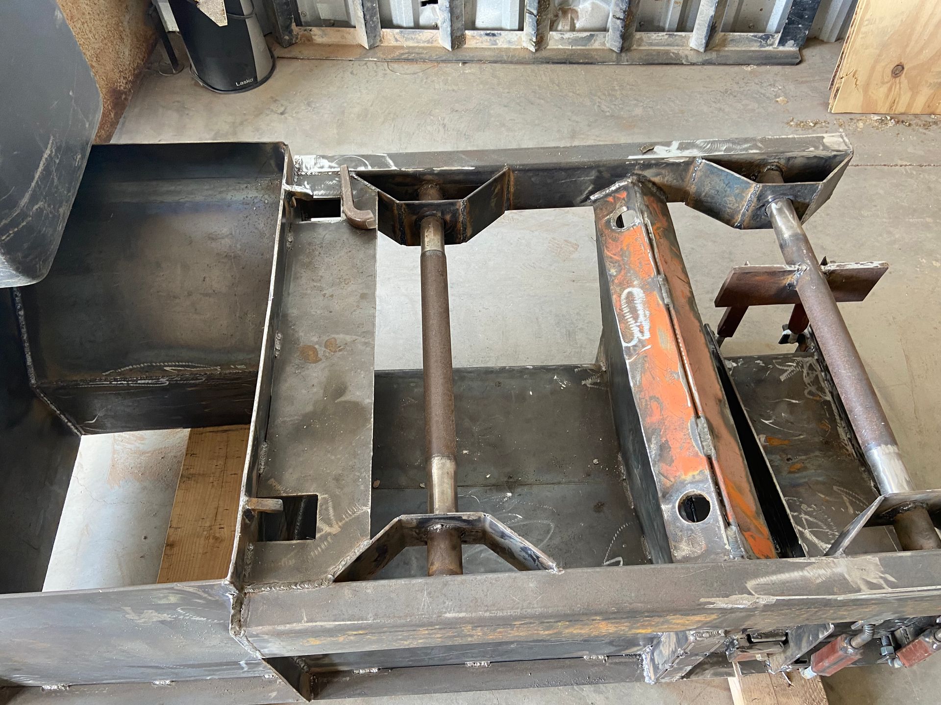 Metal frame structure with central support, likely part of machinery, on a concrete floor.