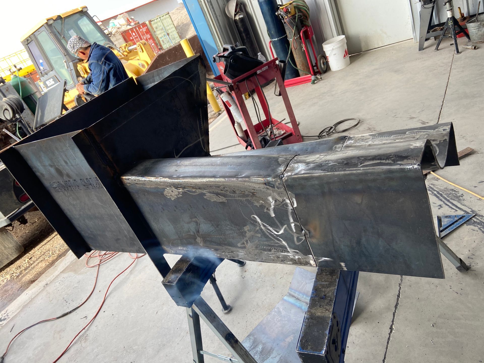 Welder fabricating a large metal structure in a workshop.