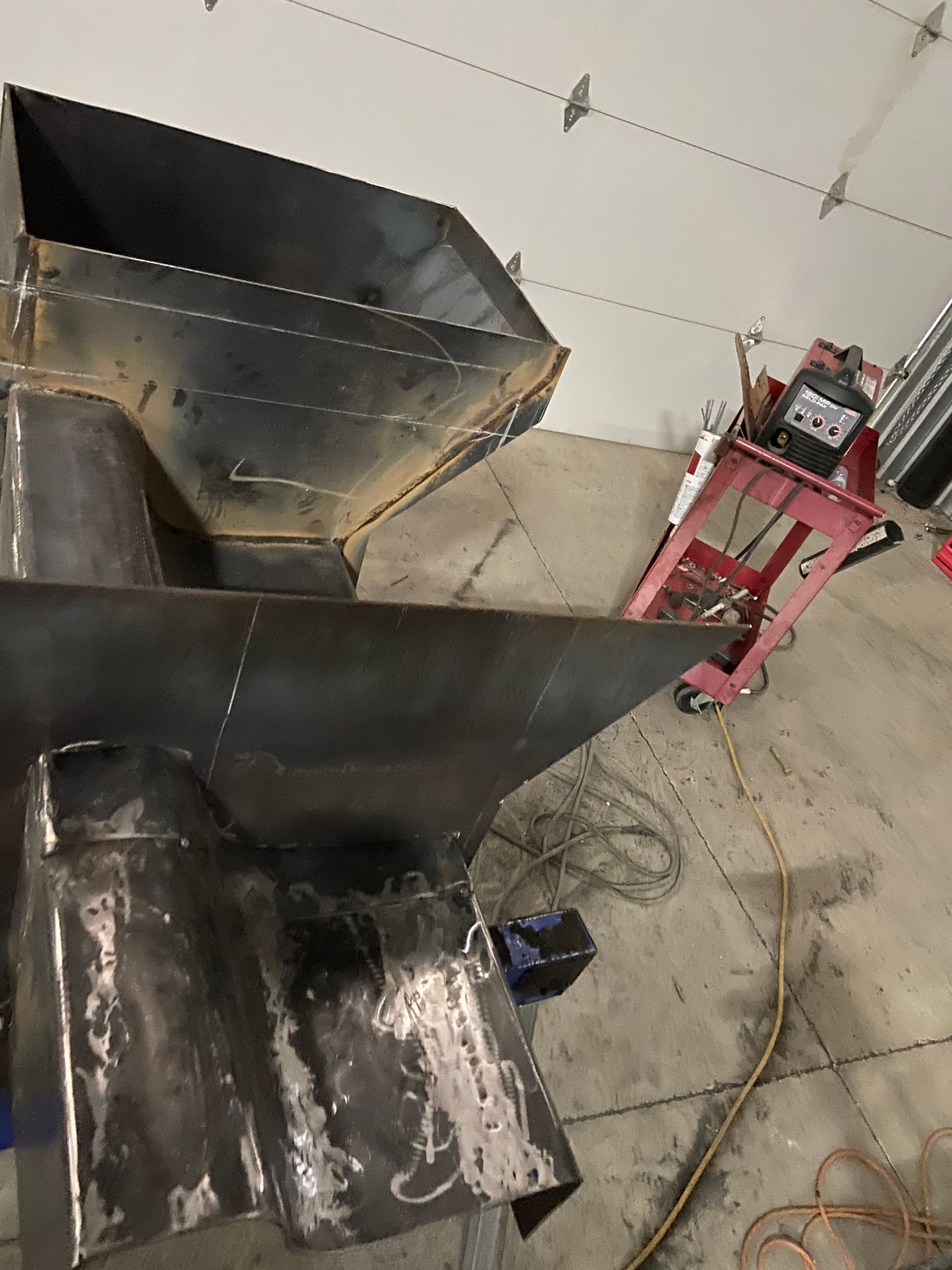 Welded metal hopper and funnel structure in a garage.