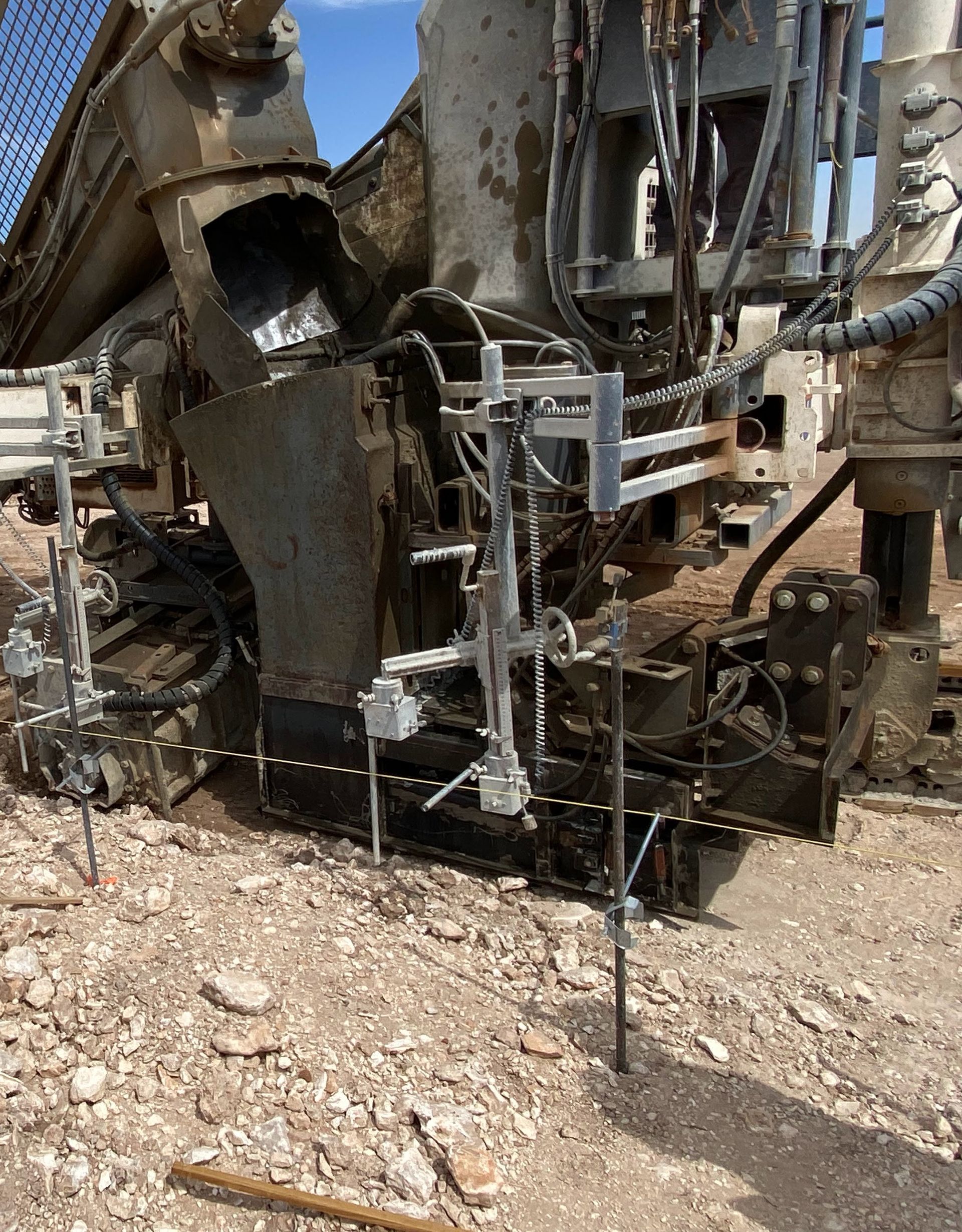 Heavy drilling machine on a construction site. Muddy, with metal equipment and supports planted in the rocky ground.