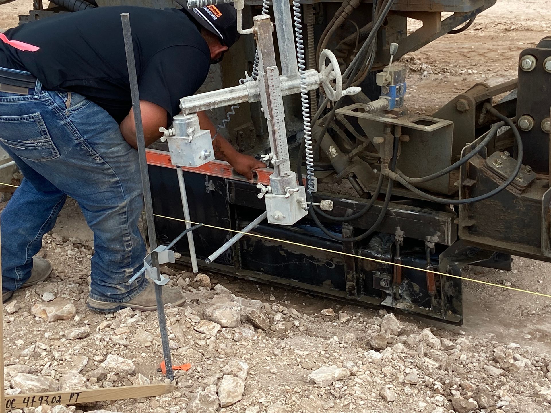 Man using a drilling machine on a construction site; ground level view.