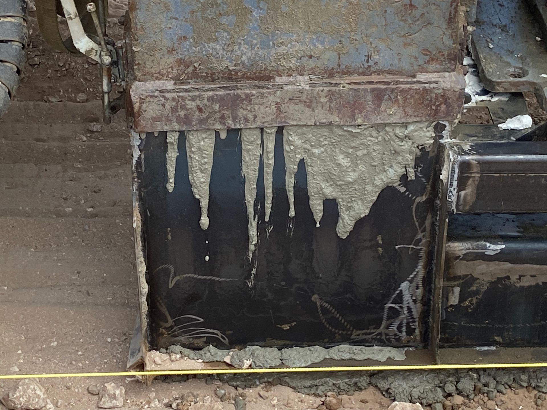 Construction equipment with hardened concrete drips on its black metal surface.