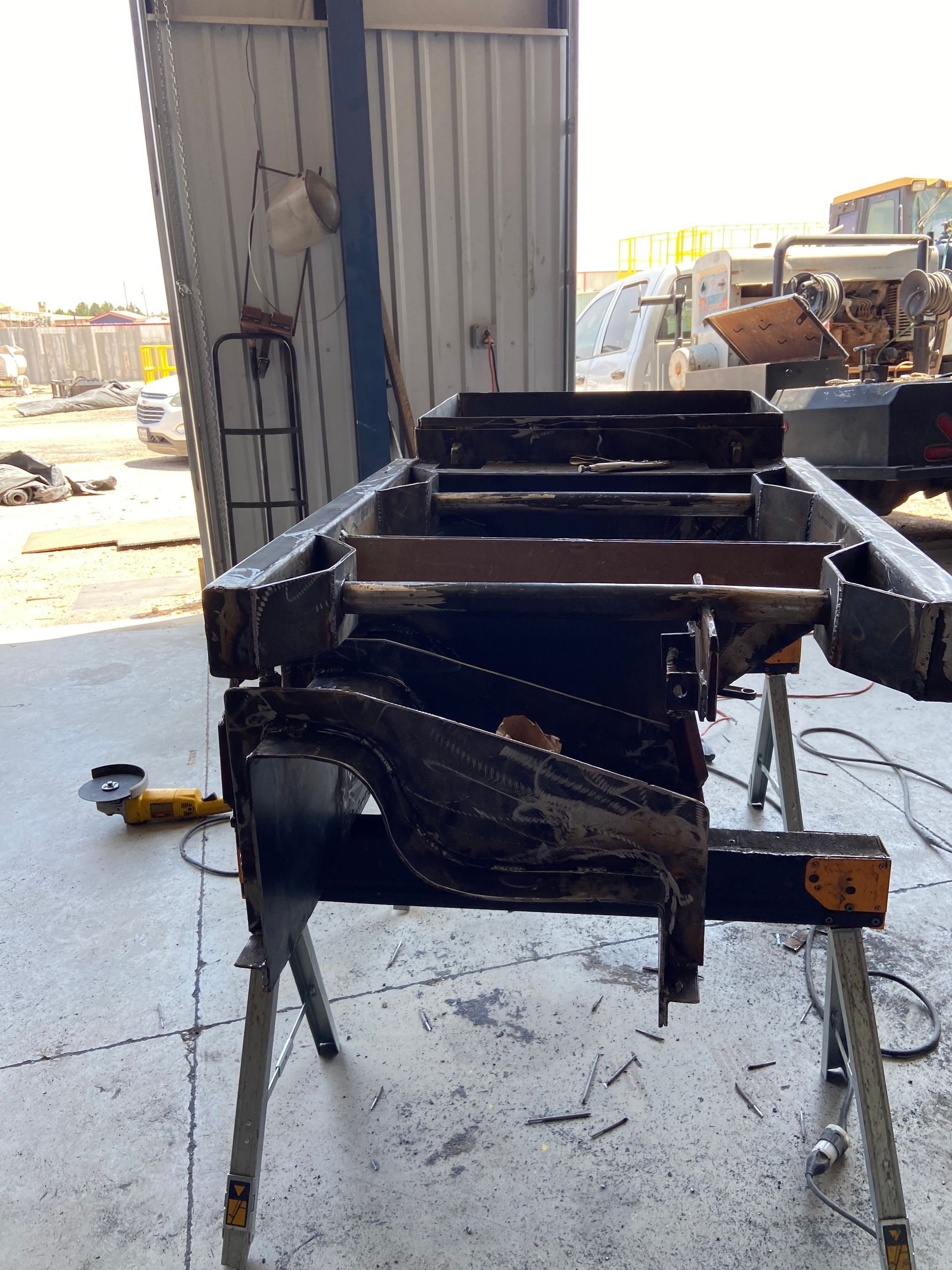 Black metal frame supported by sawhorses in a workshop.