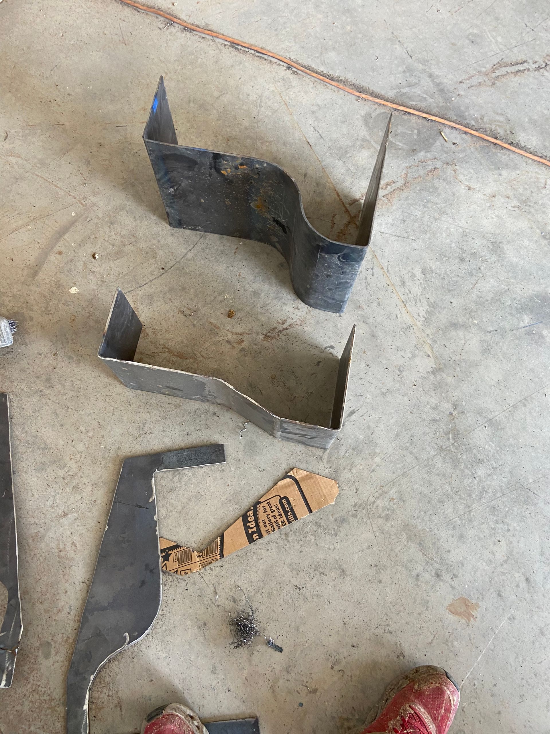 Metal brackets of varying shapes and sizes on a concrete floor.