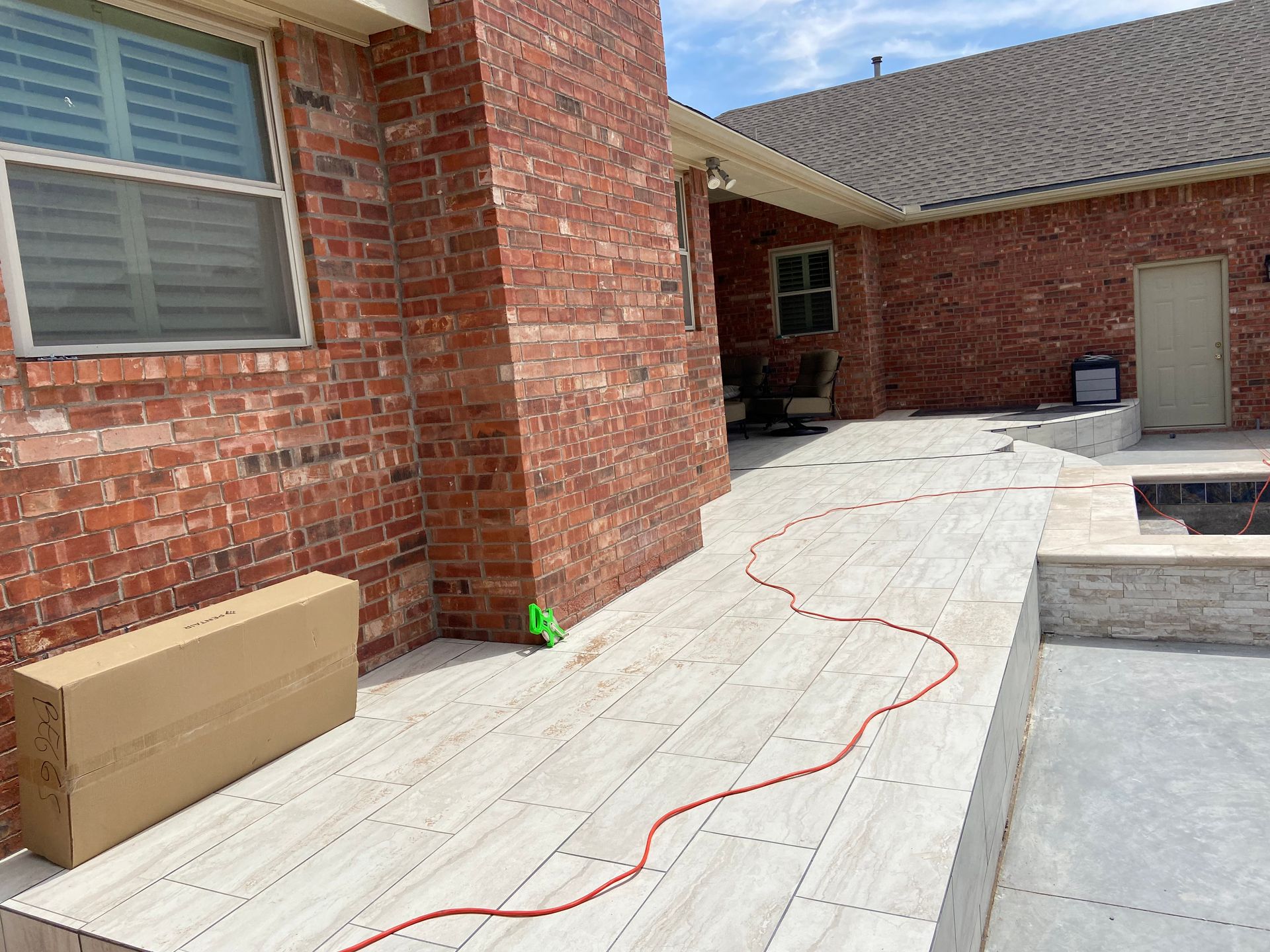 Red brick building with a light-colored tiled patio. A red cord runs across the patio.