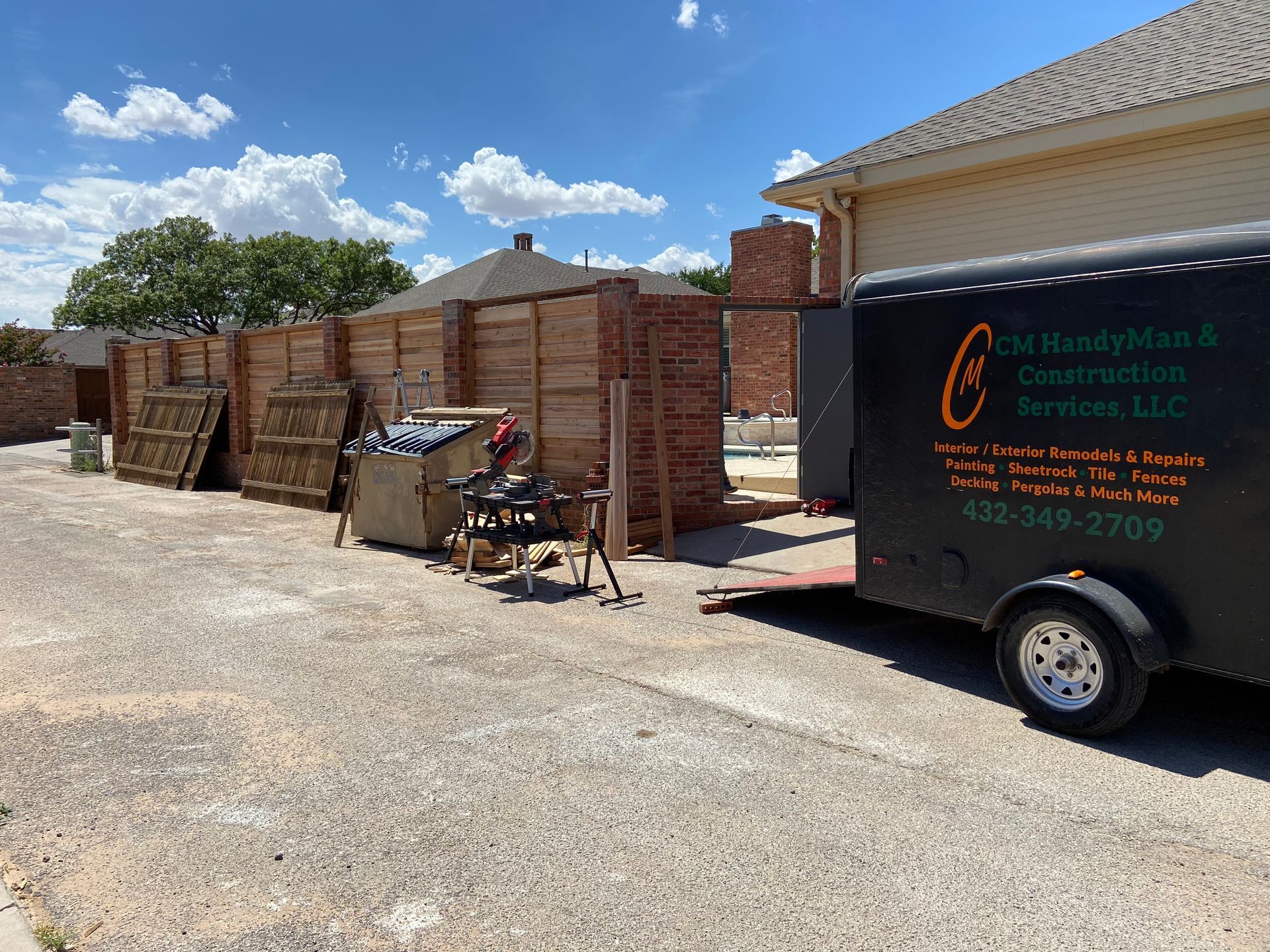 Handyman's trailer parked next to a brick wall under construction with tools on a workbench in an alleyway.