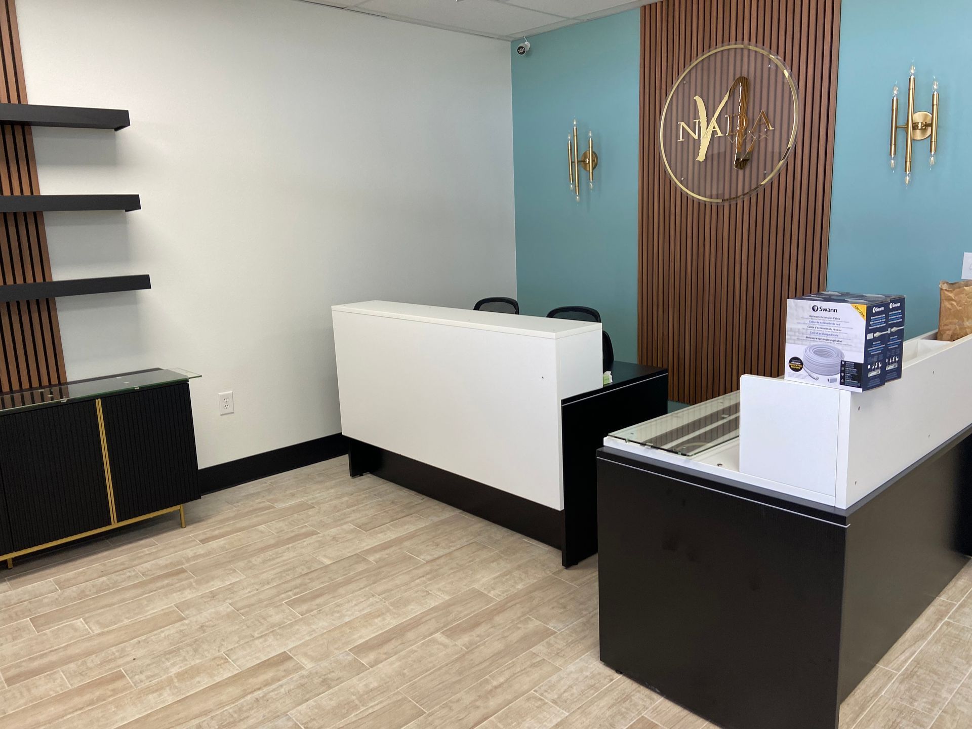 Reception area with white and black desk, wood paneling, and shelving against teal wall.