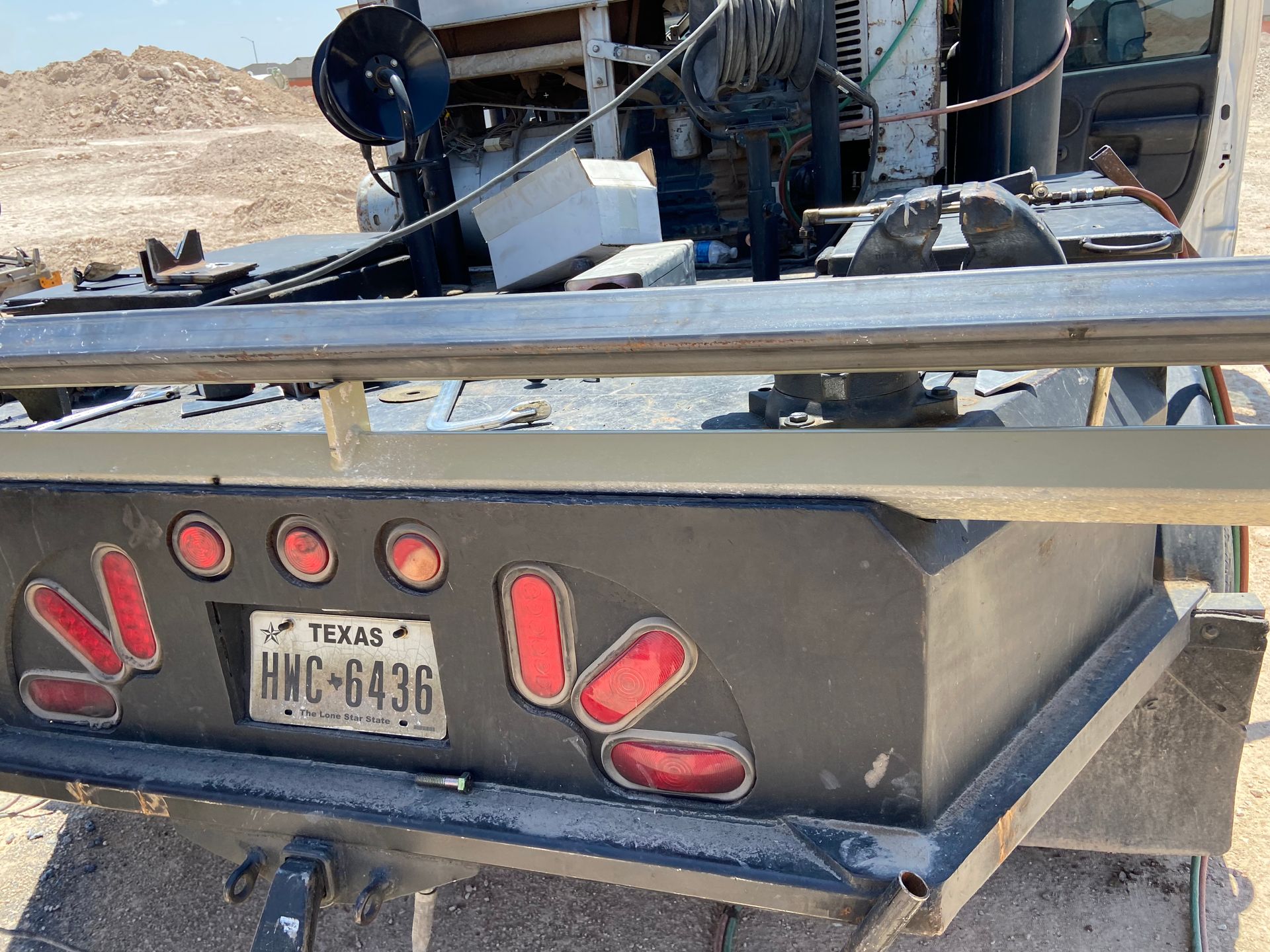Rear view of a work truck with Texas license plate, surrounded by construction materials.