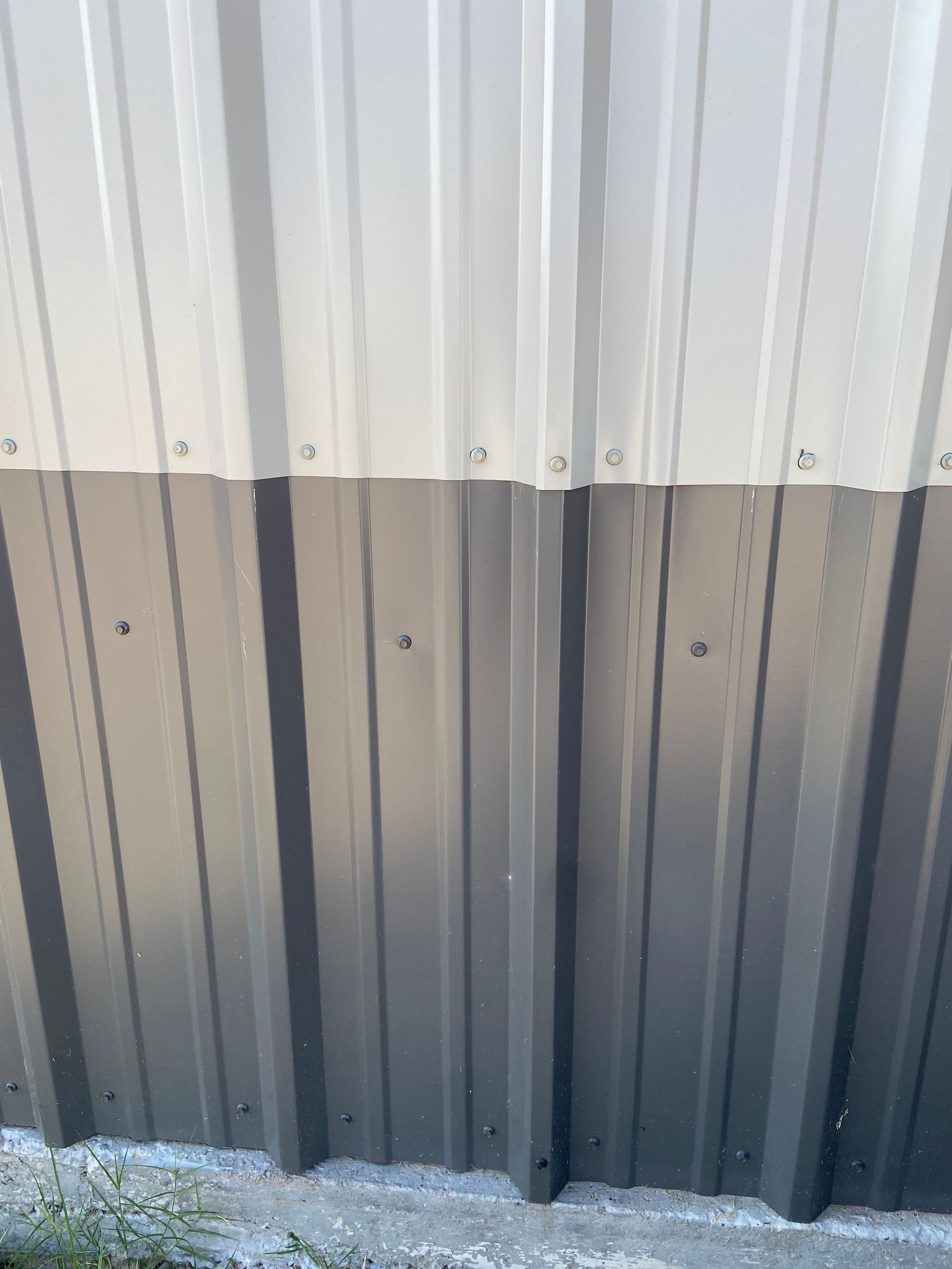 Gray and white corrugated metal siding with visible screw heads.