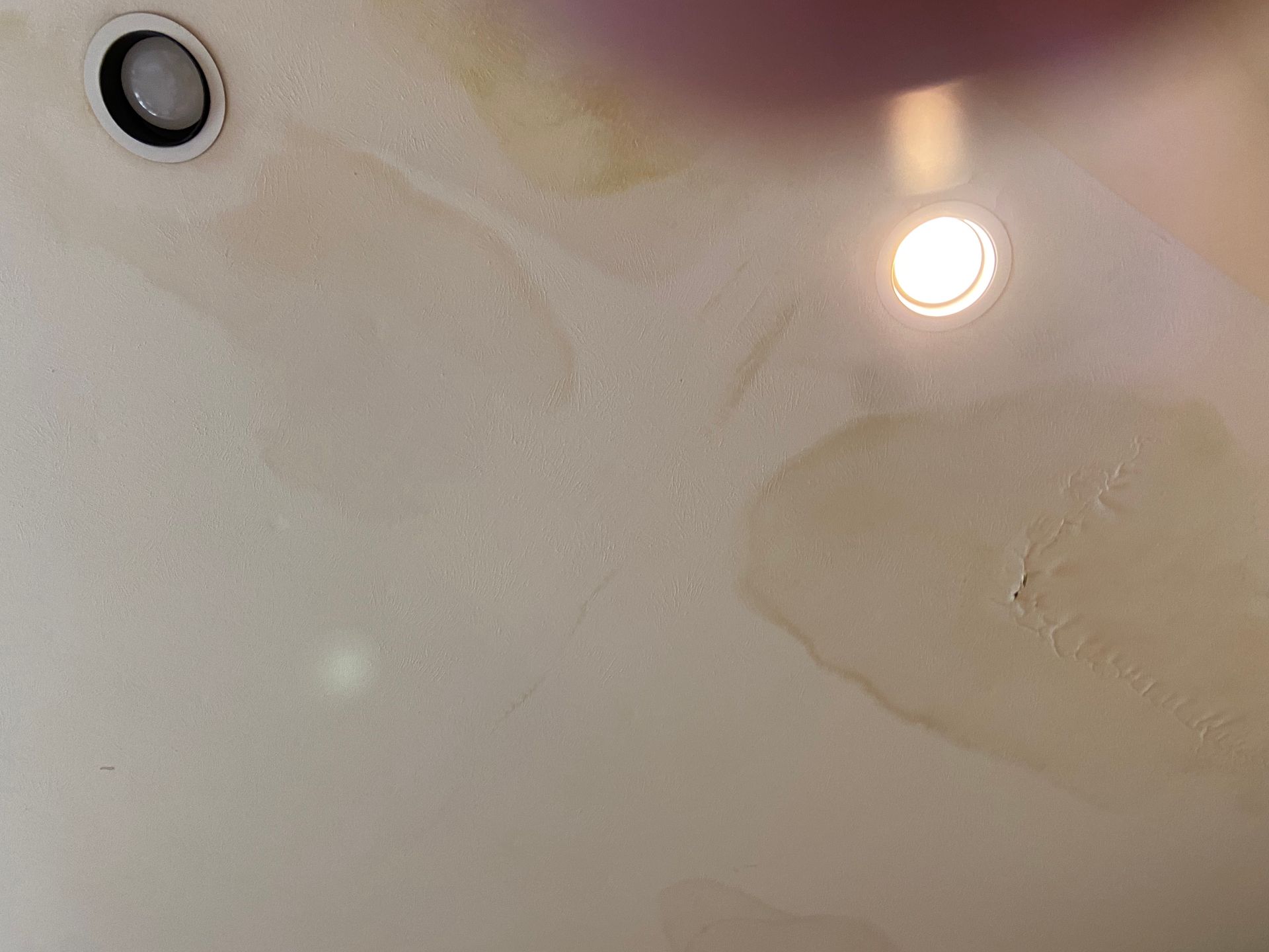 Water stains on a ceiling around recessed lights; yellowish discoloration.