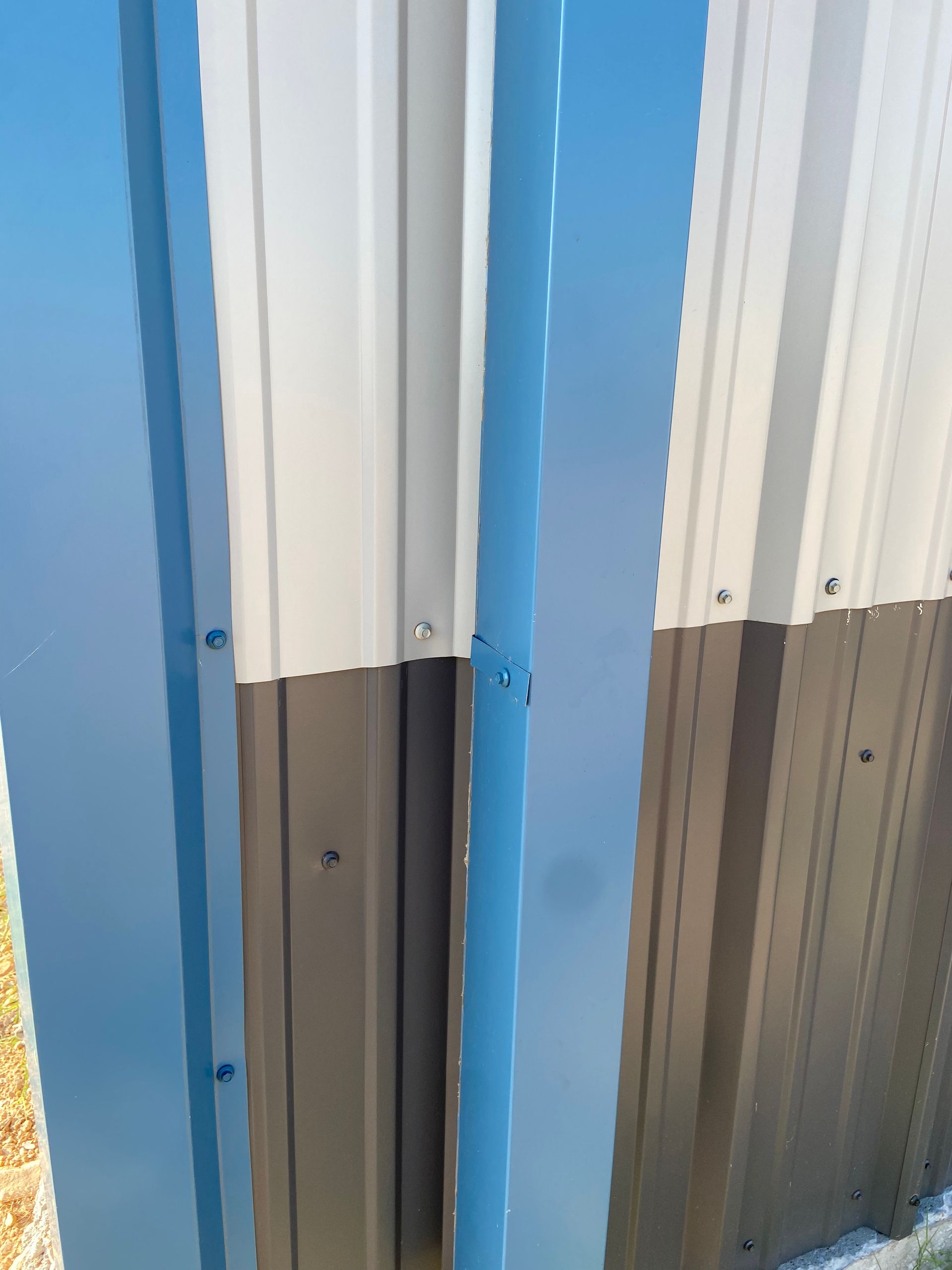 Blue vertical metal flashing between tan and brown corrugated metal siding.