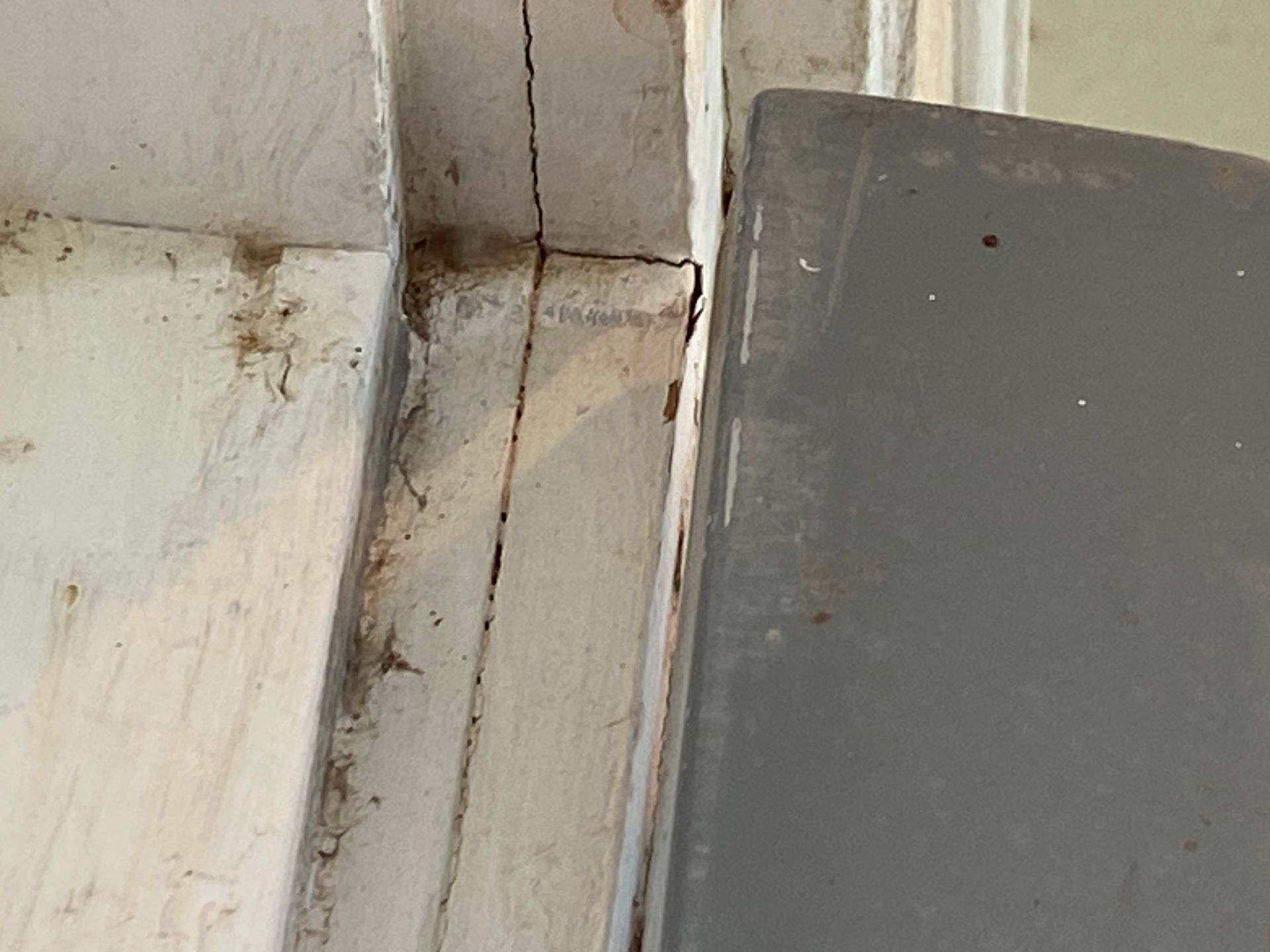 White painted window frame with cracks, gray door partially visible.