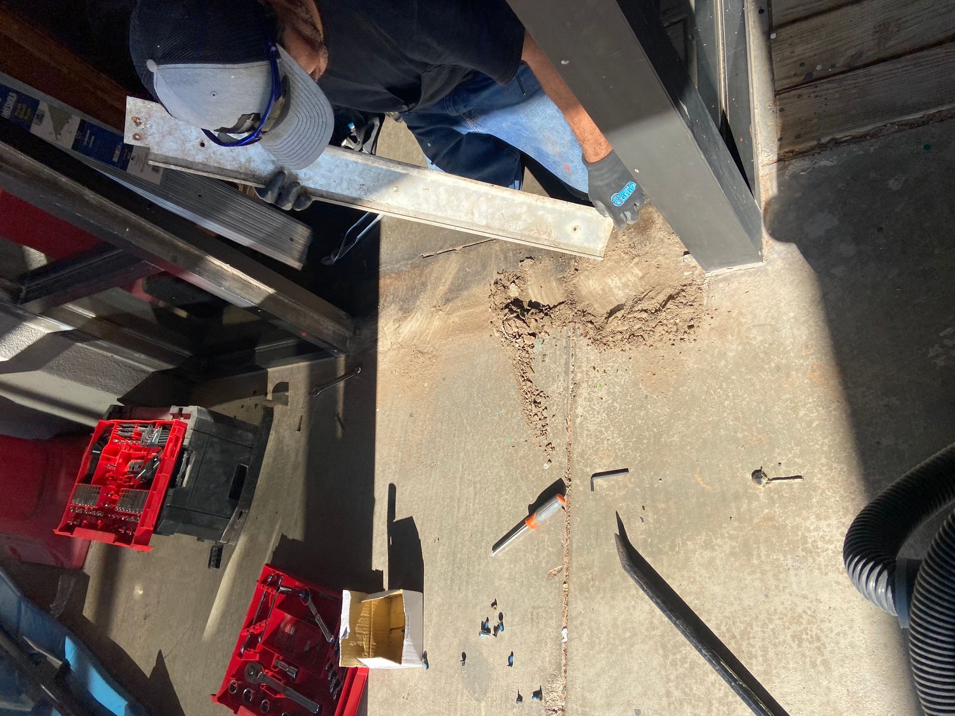 Person using a tool to clean debris on a concrete floor in a garage setting.