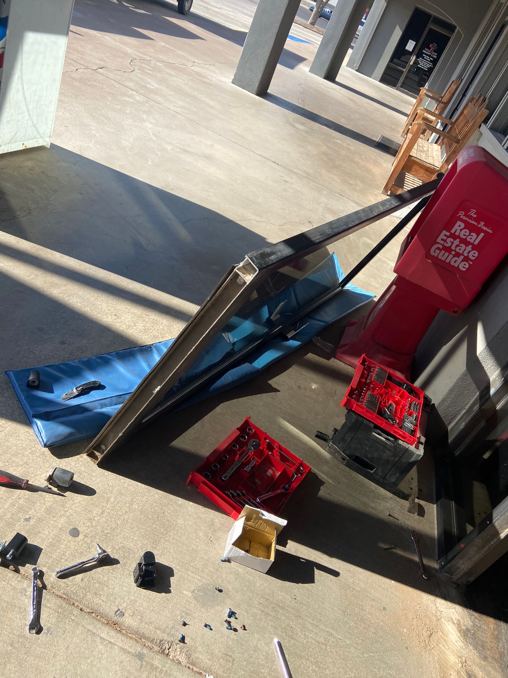 Sign with broken components on concrete. Red and blue pieces scattered. Building exterior.