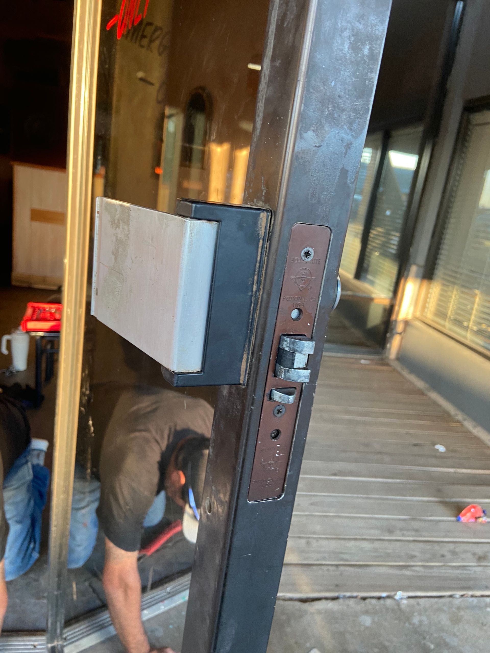 A person working on a brown door frame with a metal lock and attached metal piece.