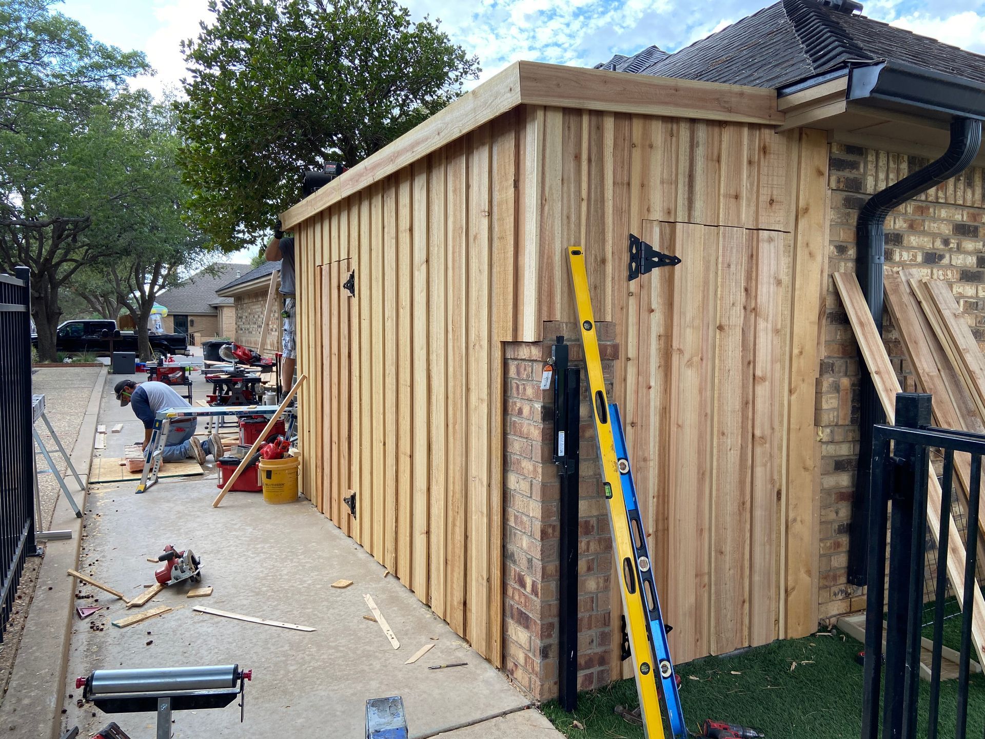 Construction workers building a wooden structure attached to a brick building.