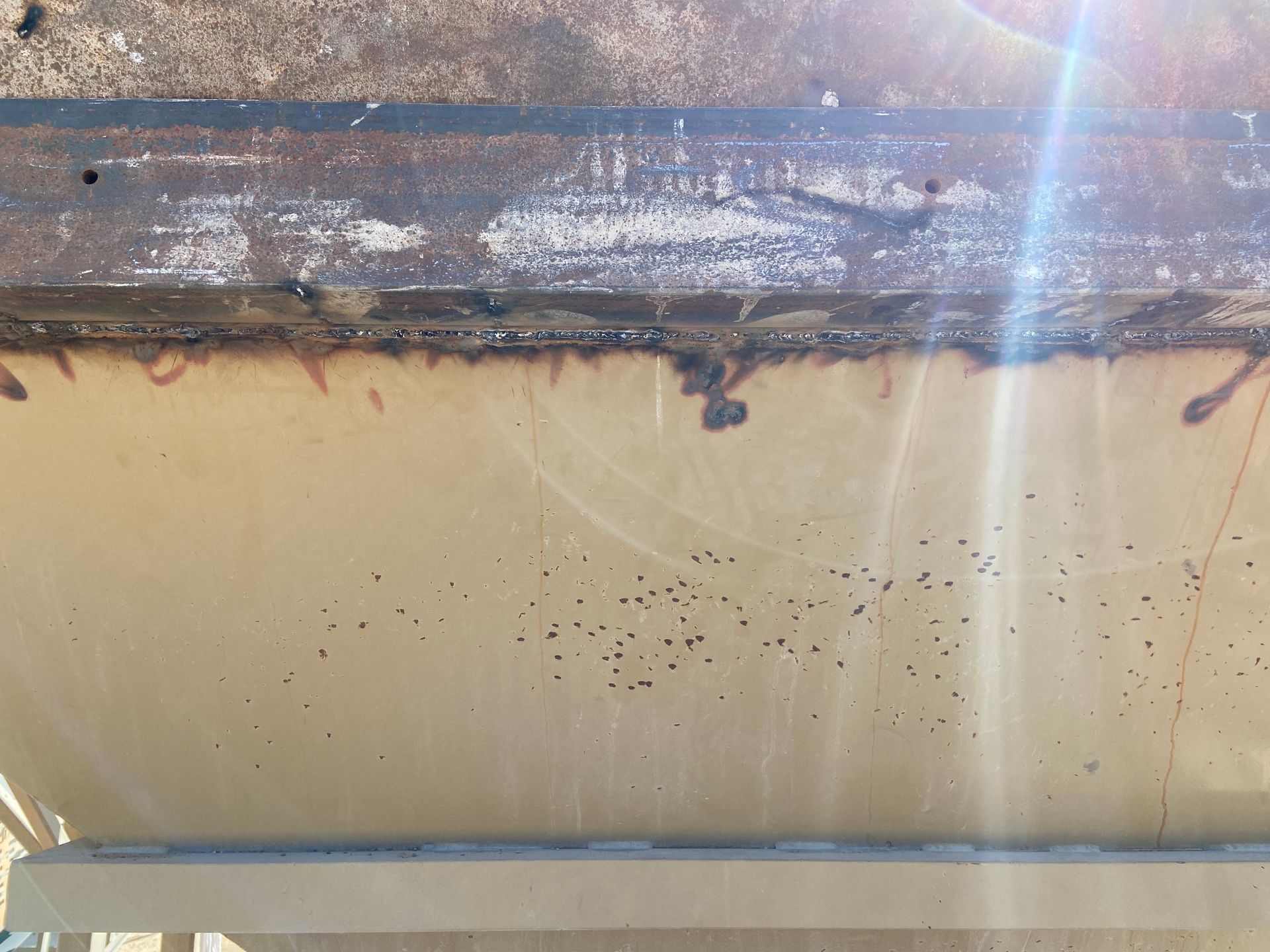 Tan and brown boat hull with visible damage and small holes.
