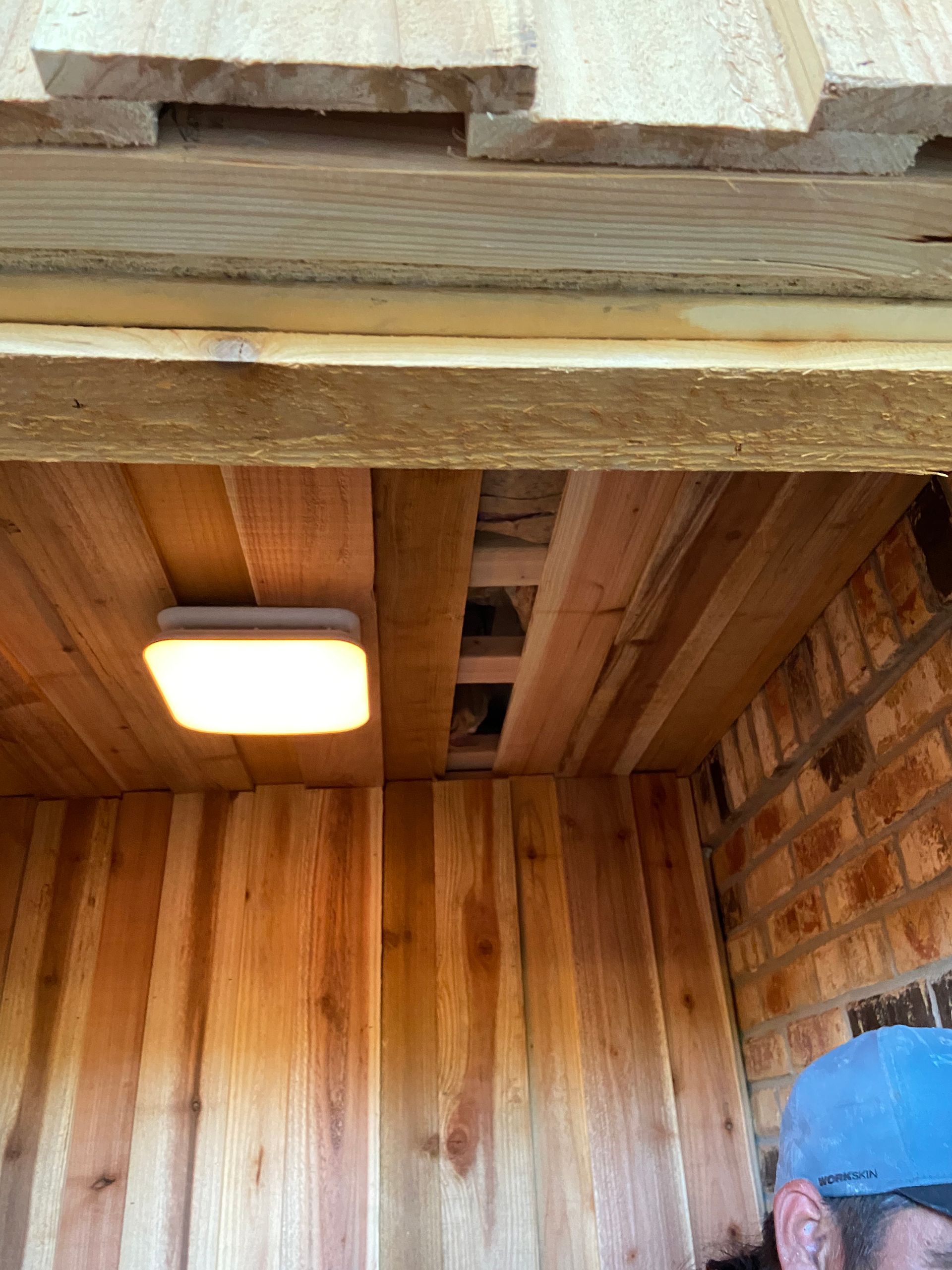 Wooden structure interior with light fixture; person visible in lower right corner.
