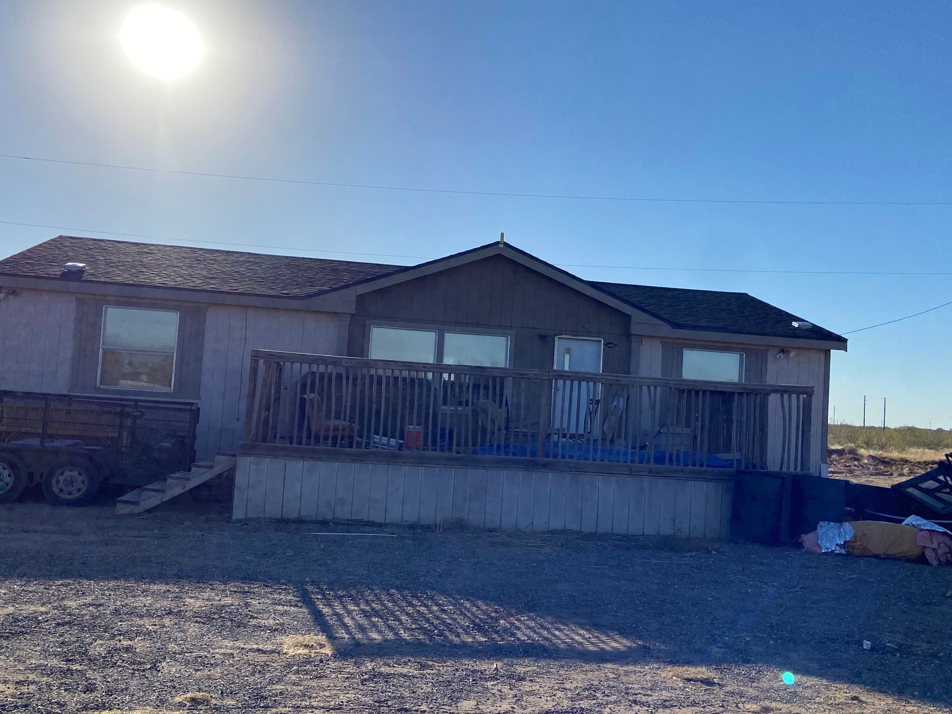 Mobile home with a deck under a bright sun.