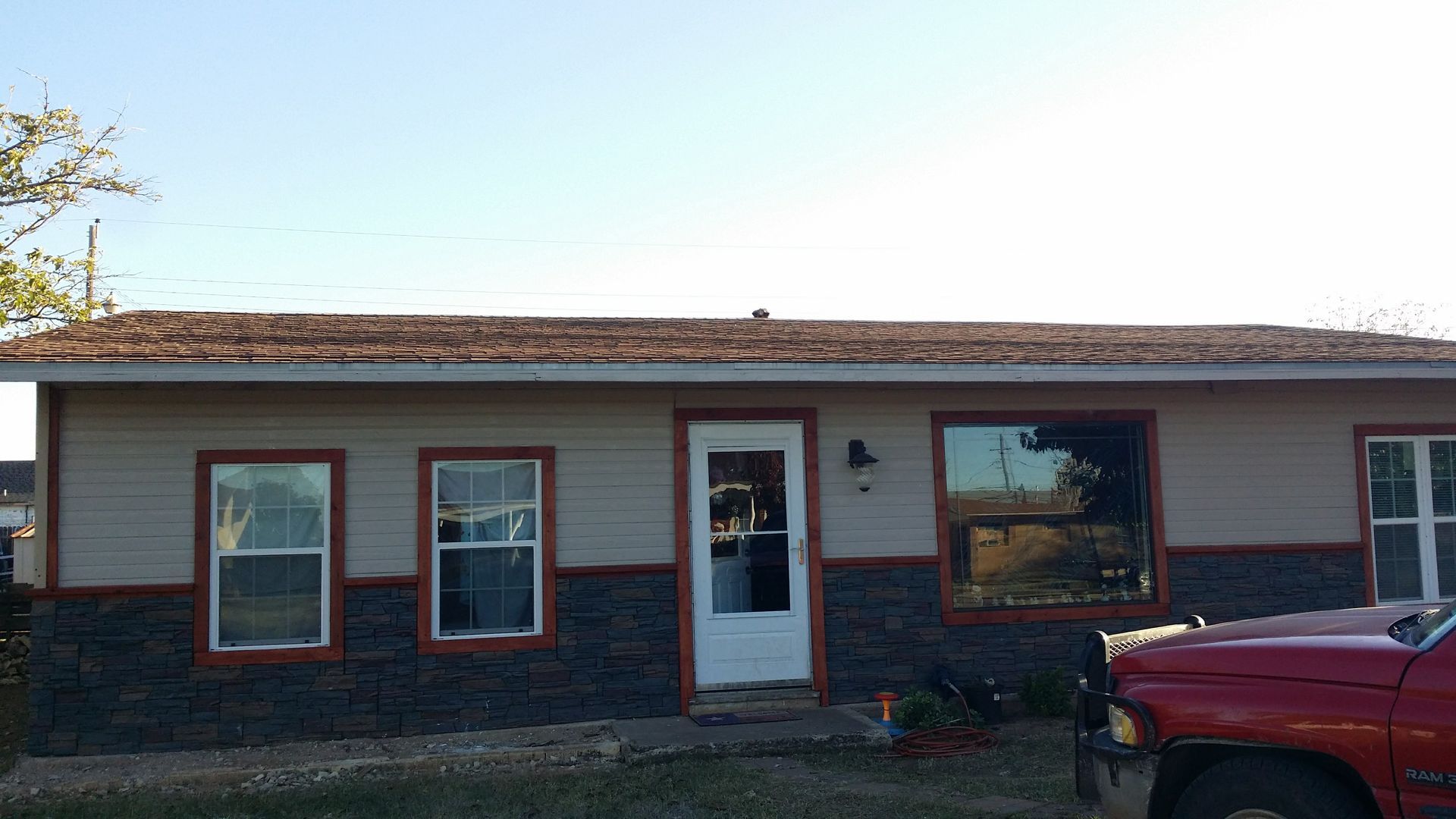 Ranch-style house with tan siding, brown trim, and a red truck parked in front.