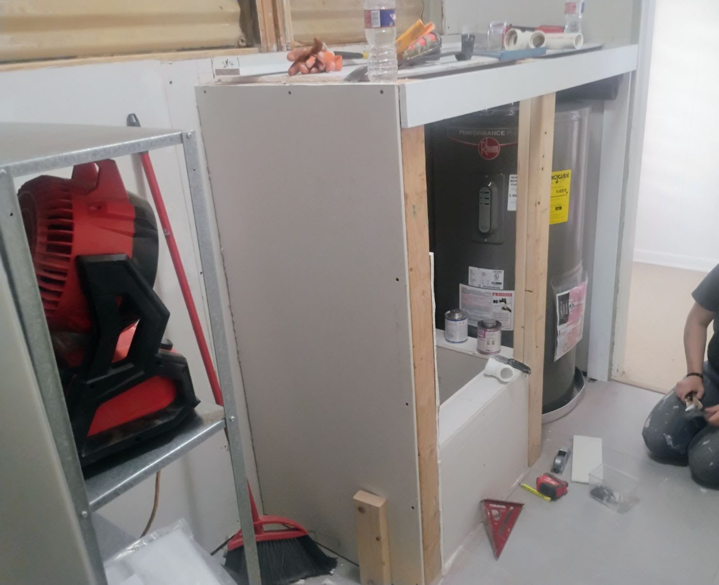 Construction in progress: drywall installed around water heater in a utility room.