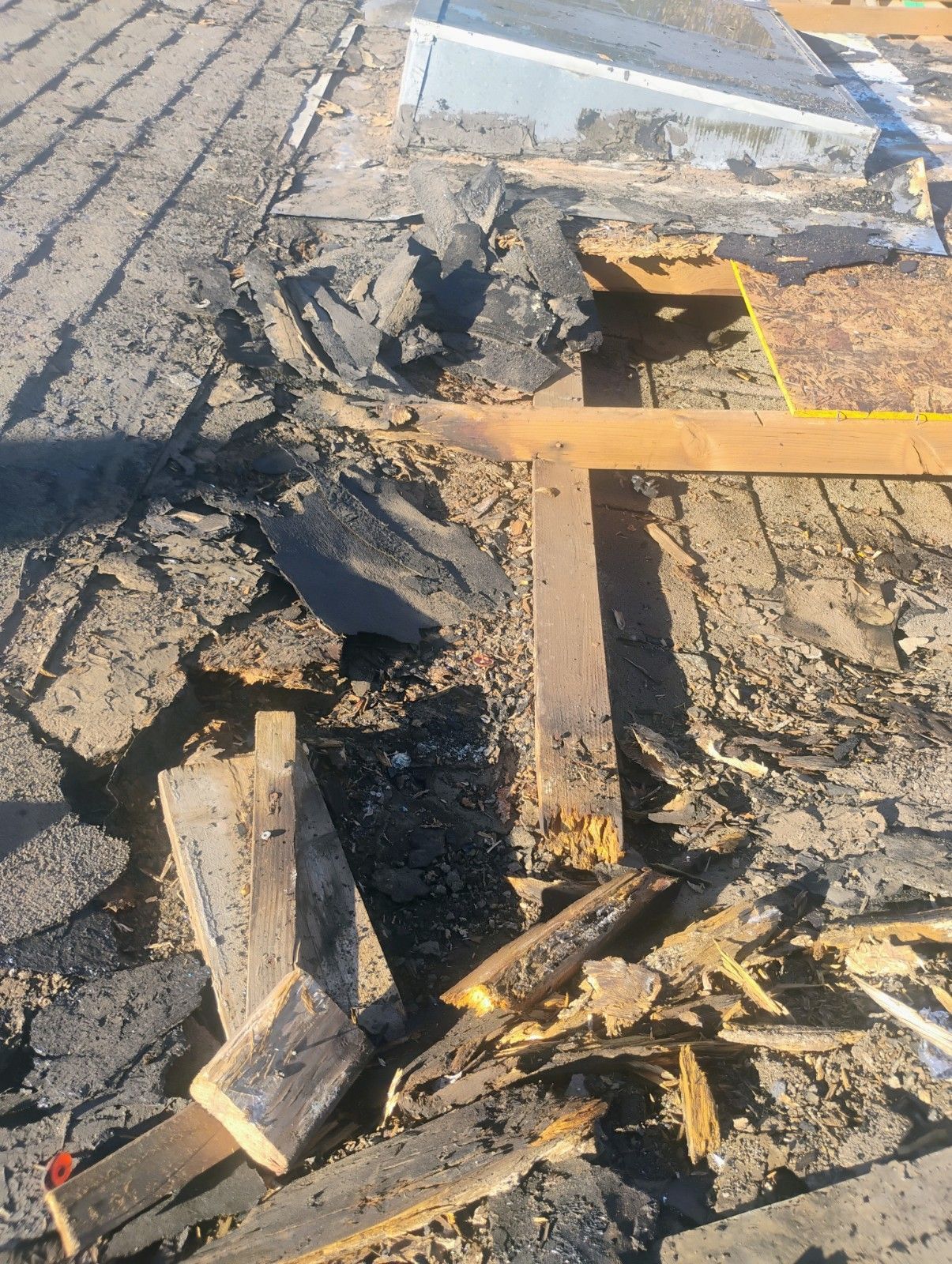 Damaged roof showing exposed wooden beams and roofing materials in disrepair.