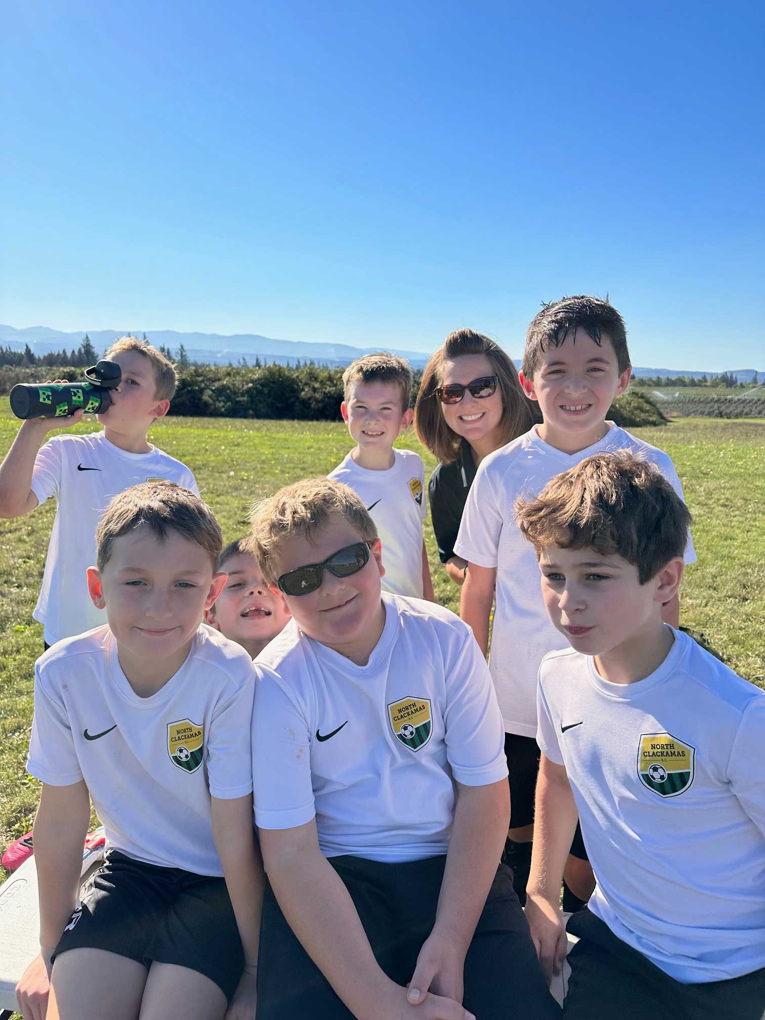 Soccer team poses for photo outdoors on a sunny day.
