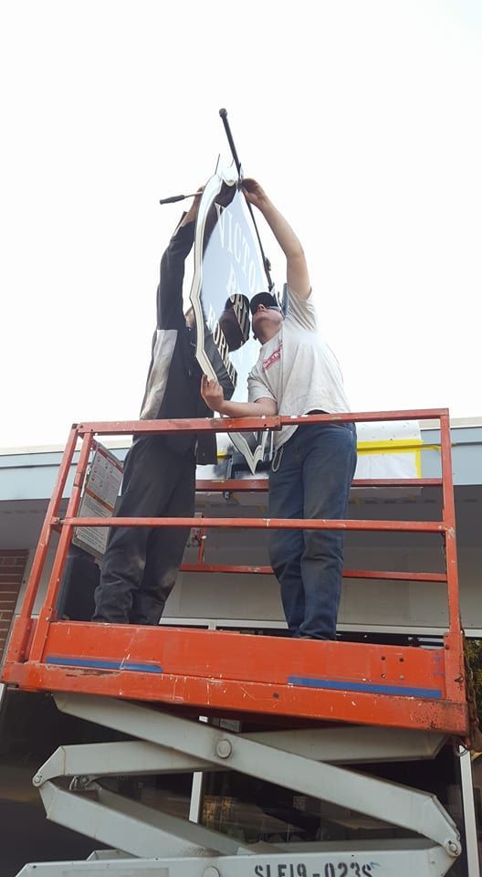 Two workers hanging a sign