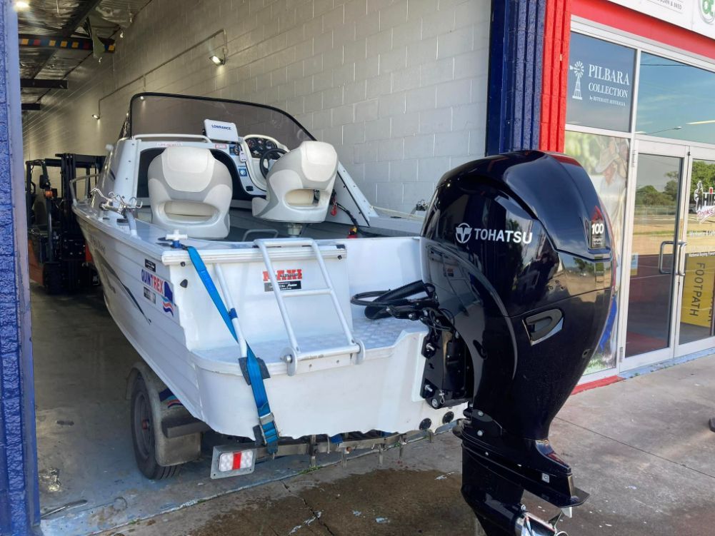 White Motorboat With Black Engine, Blue Strap, Parked Outside a Shop — In Tune Marine in West End, QLD