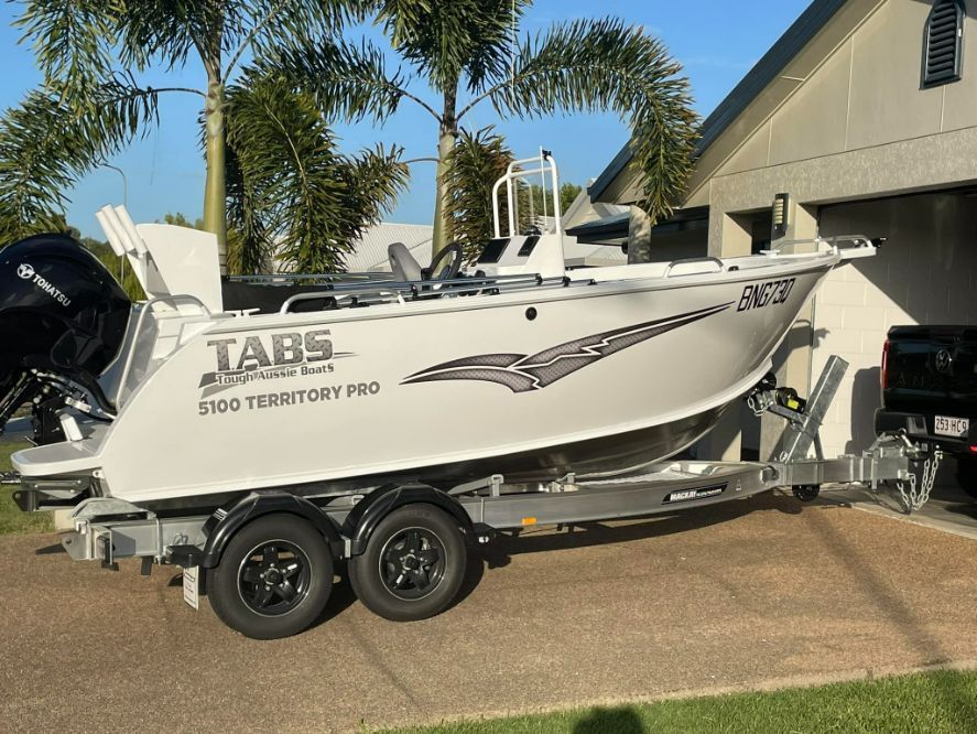 A White TABS 5600 Territory Pro Boat On A Trailer, Outdoors Near A House — In Tune Marine in Mackay, QLD