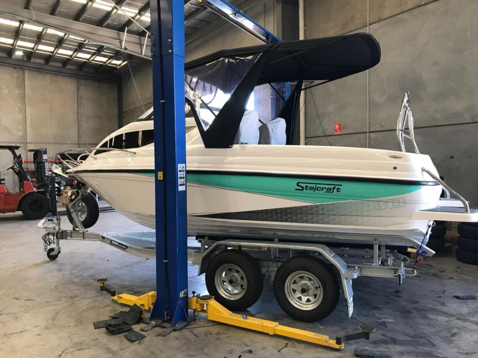 A White Boat With Teal Accents is on a Trailer in a Garage — In Tune Marine in Mackay, QLD