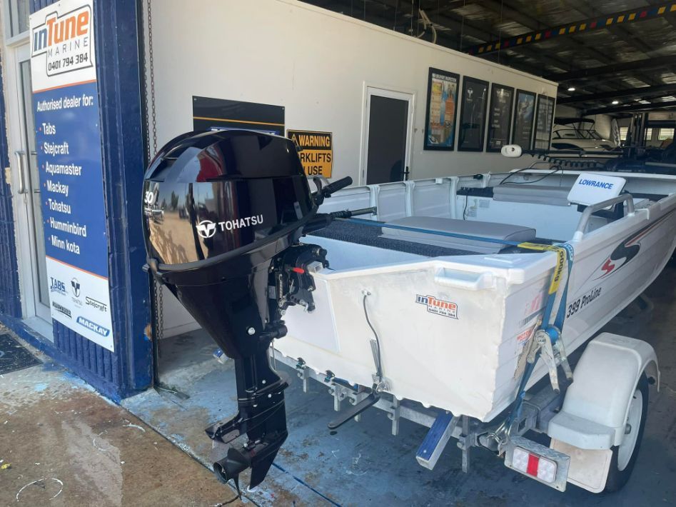 A White Boat With a Black Motor on a Trailer in Front of a Shop — In Tune Marine in West End, QLD