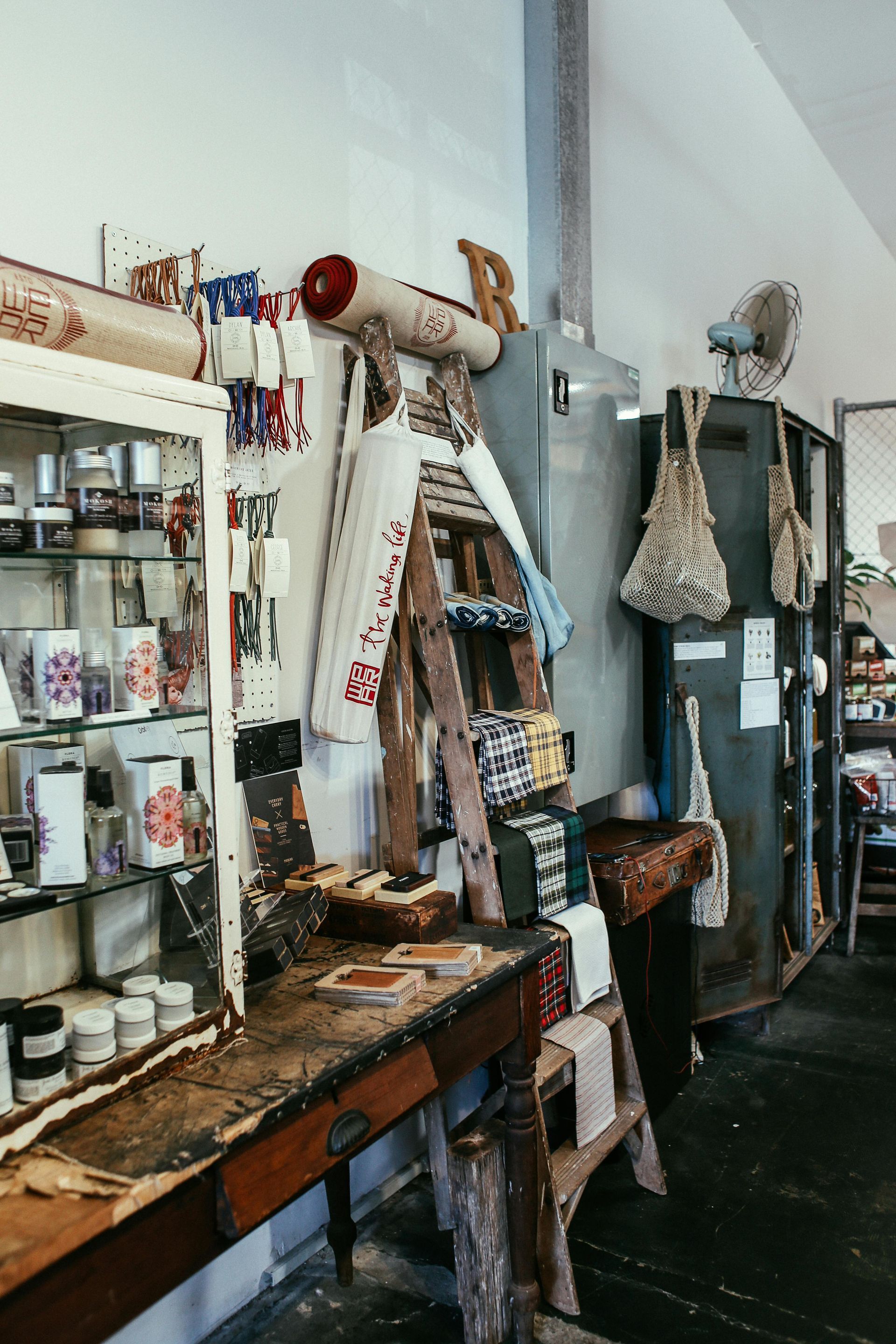 A cluttered antique shop interior. Shelves, table, and a ladder display items.