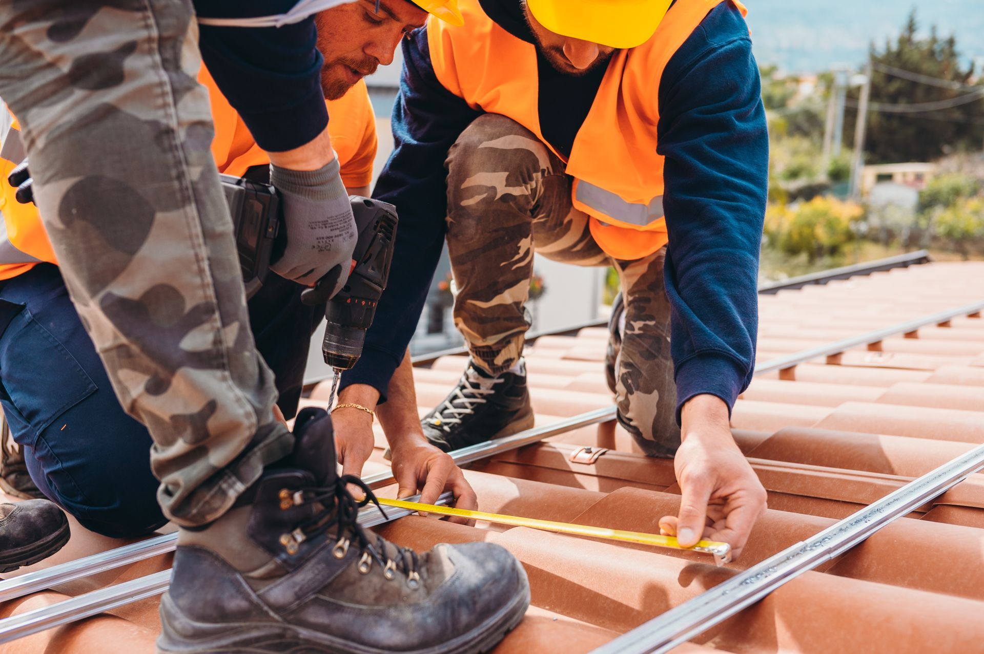A team of male workers work on the tiled roof of a house. A team of male workers work on the tiled roof of a house.