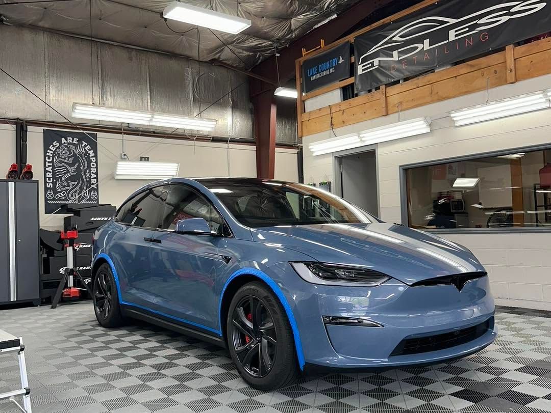 Blue sports sedan in a garage, viewed from the front-left side.