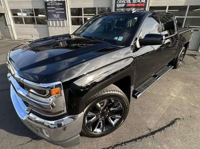 Black GMC pickup truck parked outside a dealership on a sunny day