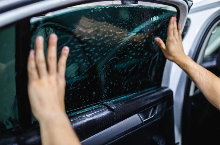 Hands pressing a cracked car side window from inside a vehicle