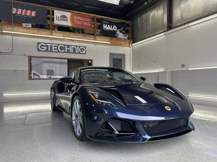 Dark blue Ferrari parked in a showroom with GTECHNIQ signage