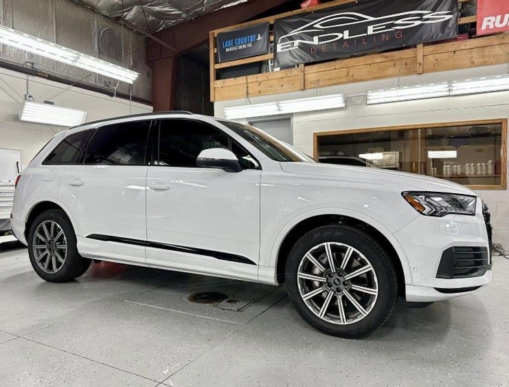 White SUV parked inside a showroom or garage, side view on a clean floor