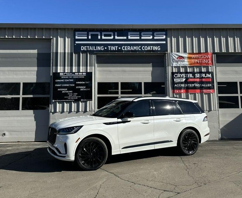 White SUV parked outside Endless detailing shop with ceramic coating signs
