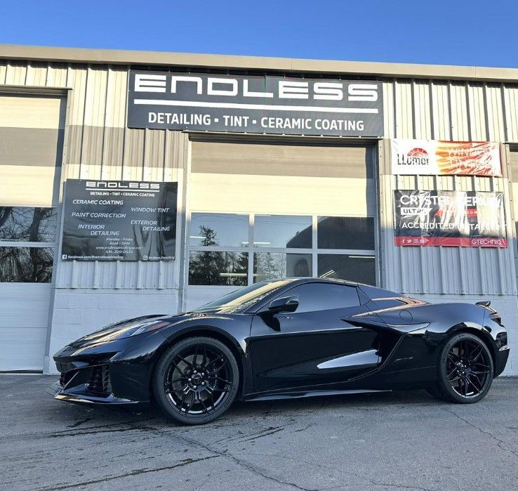 Black sports car parked outside Endless detailing shop with tint and ceramic coating sign