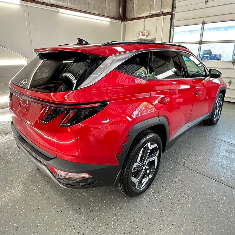 A red hyundai tucson is parked in a garage.