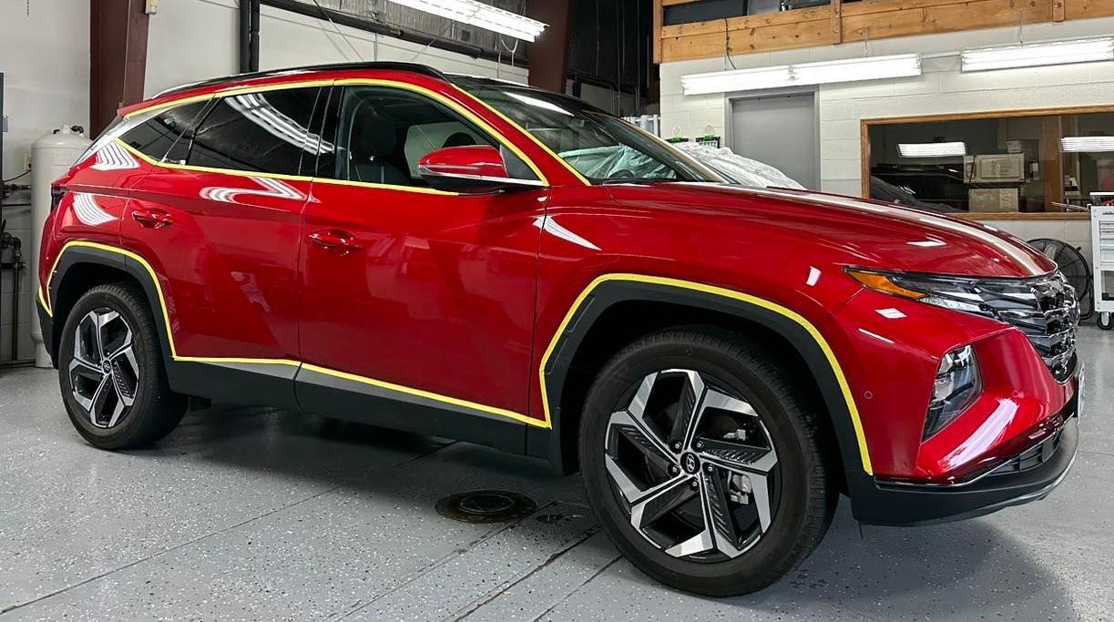 A red suv is parked in a garage with yellow stripes on the side.