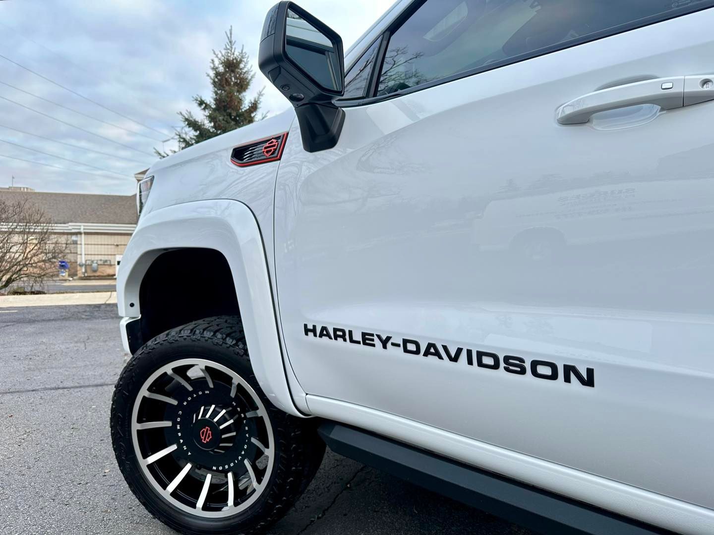 White Harley-Davidson truck with black lettering, black and silver wheels, and red emblem on the side.