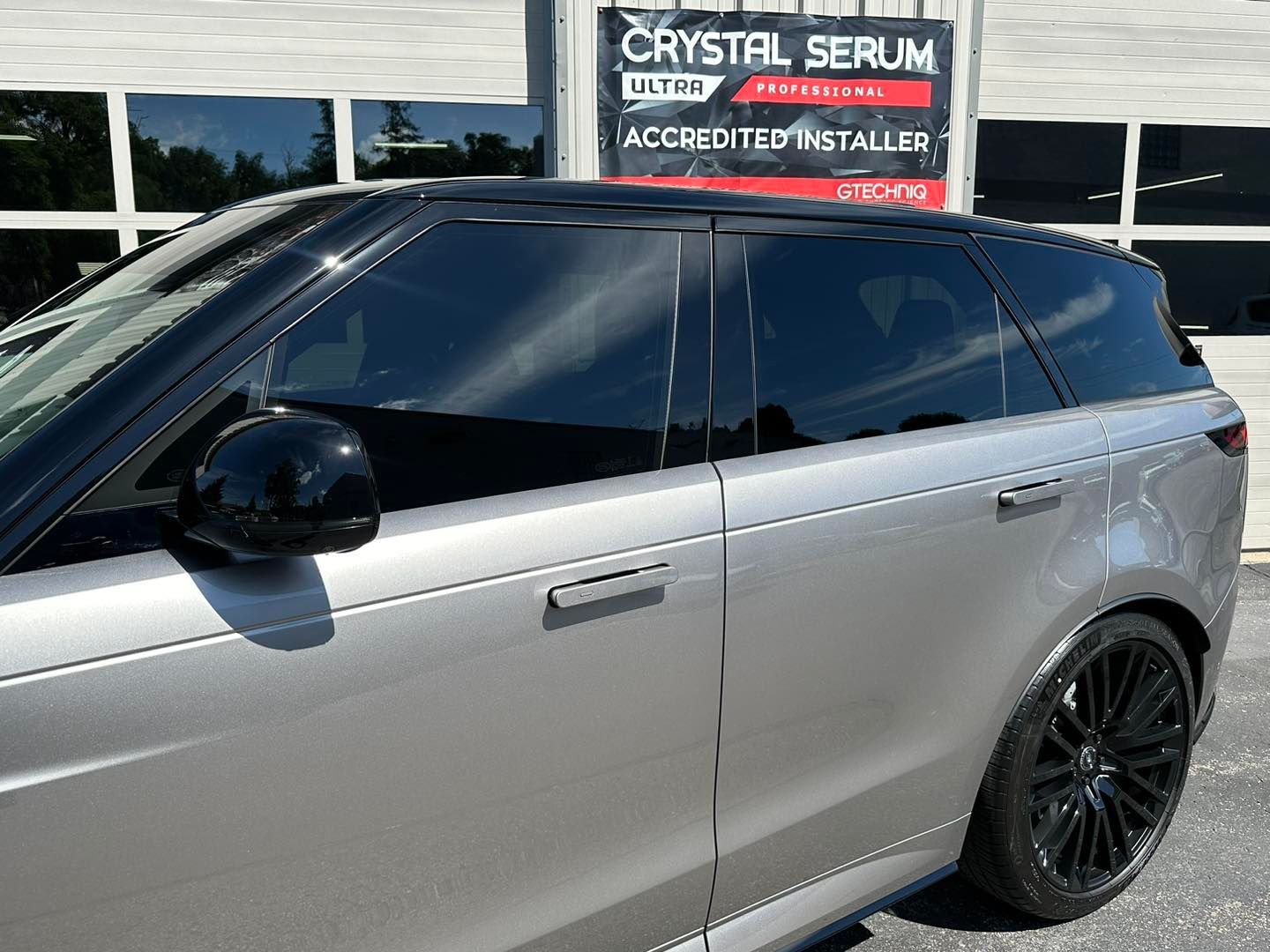 A silver range rover is parked in front of a crystal serum sign.