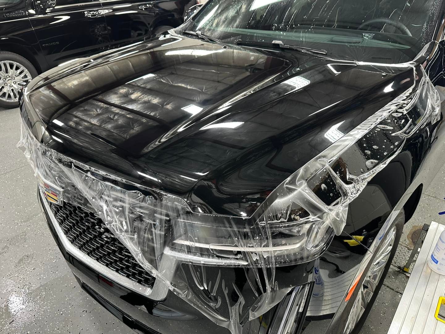 Black car with protective film on the hood and front, indoors.