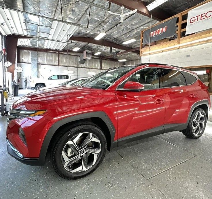 Red SUV parked inside an auto shop showroom, viewed from the front-left side.