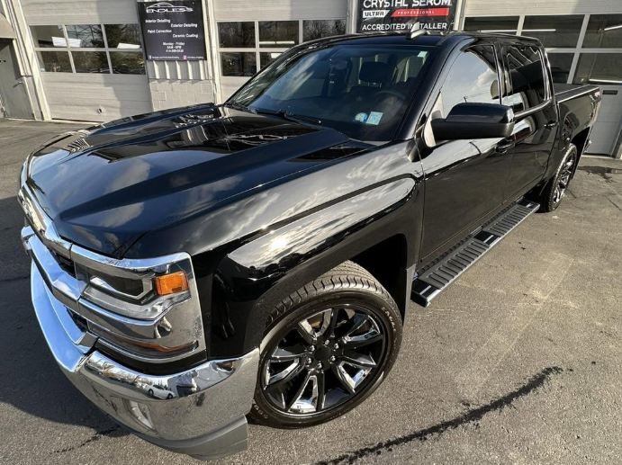 Black pickup truck parked outside a dealership, shown from the front-left angle.