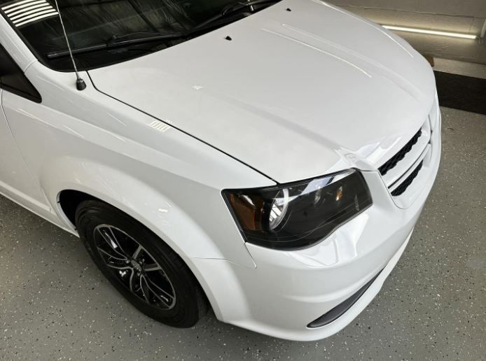 White sedan parked indoors, viewed from the front-left corner.