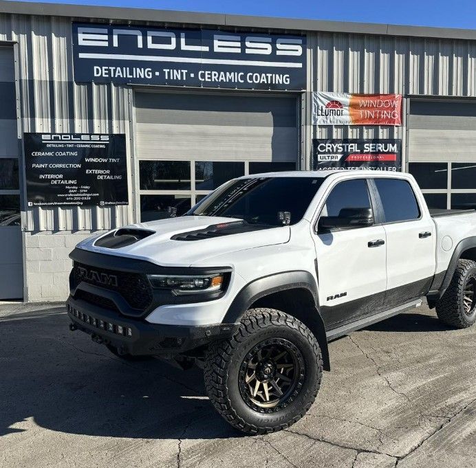 White lifted pickup truck parked outside an auto detailing shop.